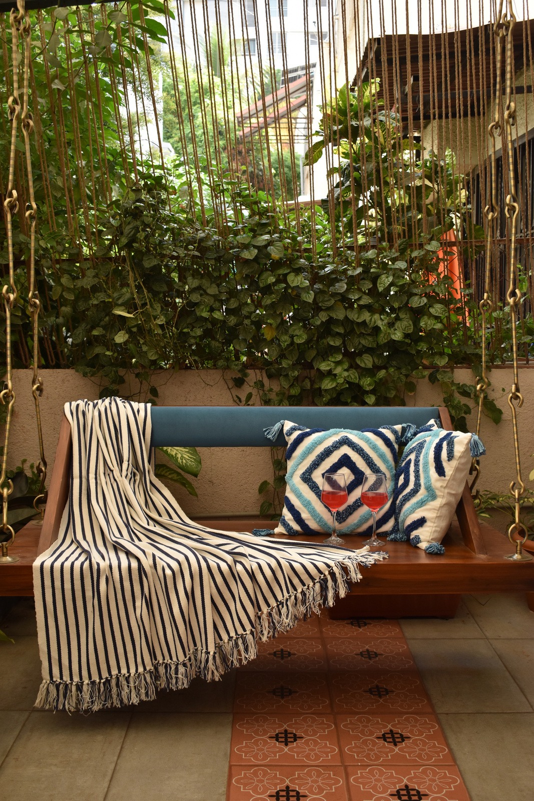 Covered morning veranda with handcrafted teak swing and terracotta tiles